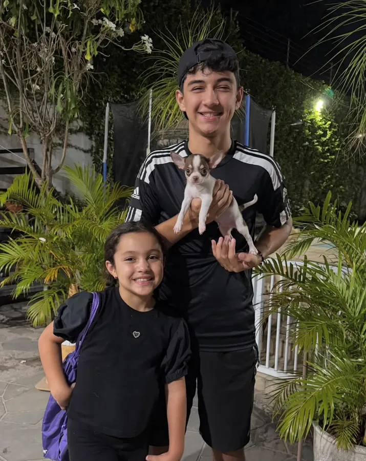 A teenager and his younger sister holding their new chihuahua puppy