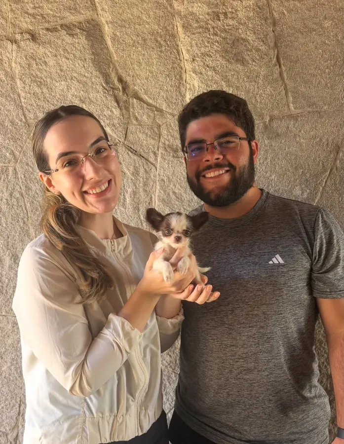 A couple holding a long haired chihuahua puppy